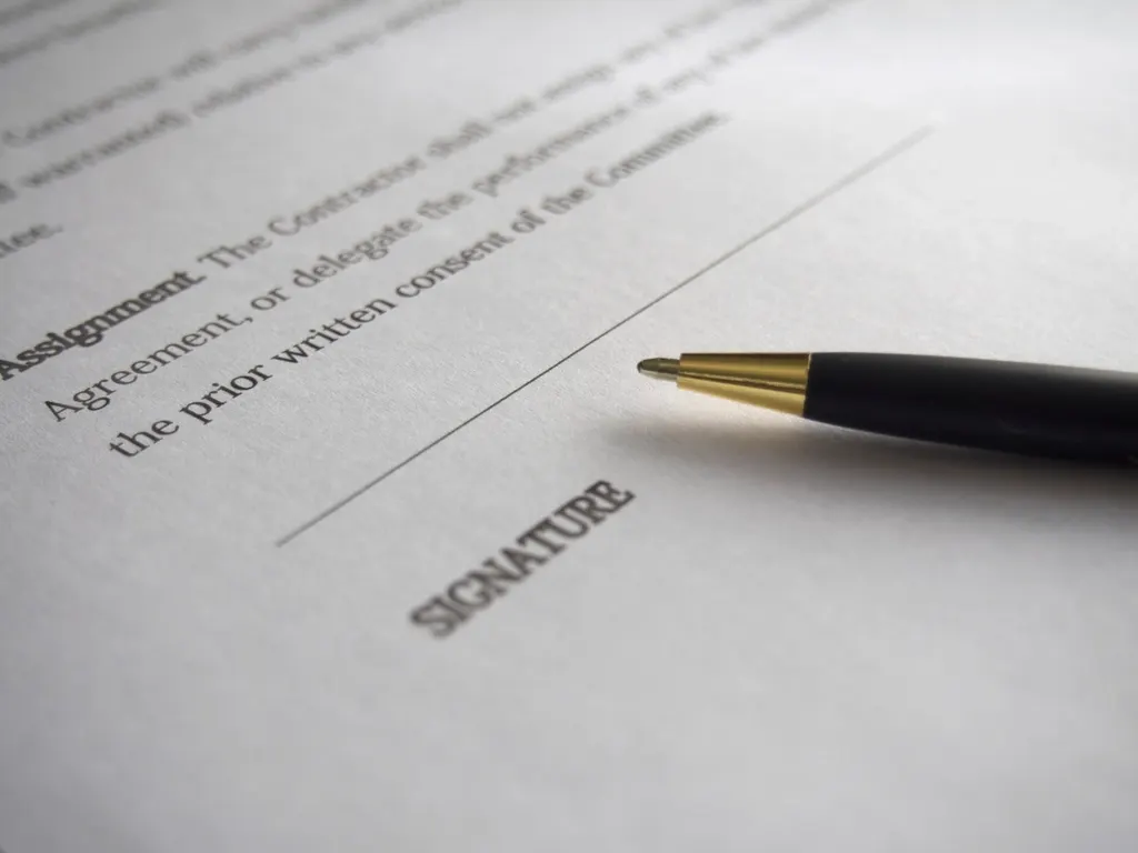 A pen resting beside the signature line of a printed agreement.